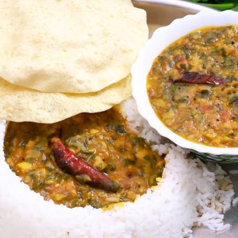spinach dal served in a plate with white rice and papadams